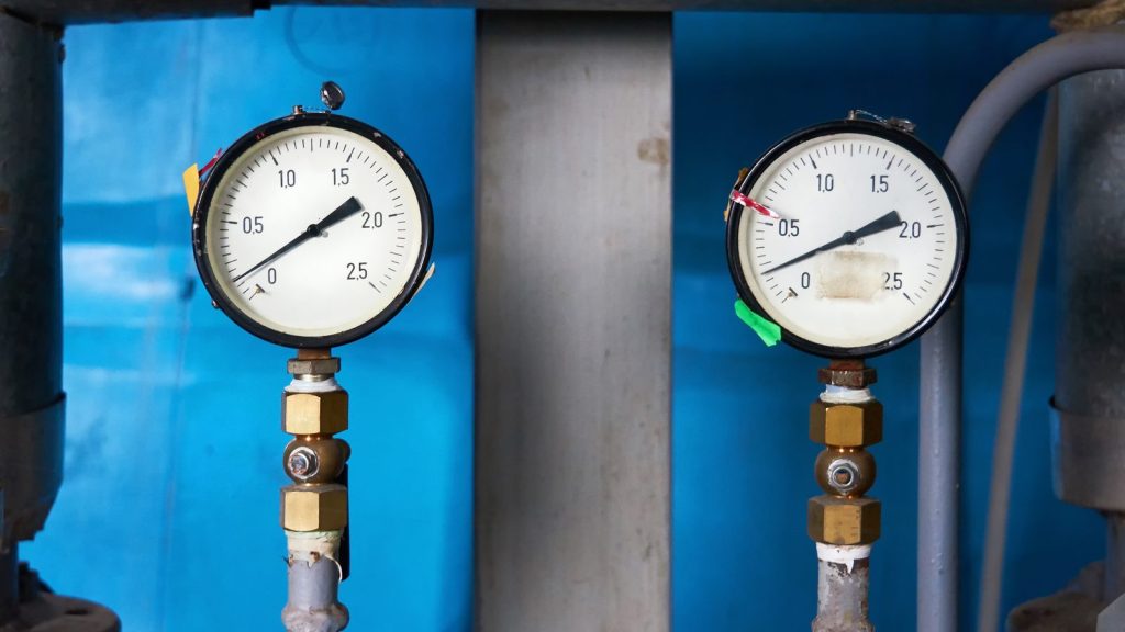 Two pressure gauges on either side of a filter housing showing different readings