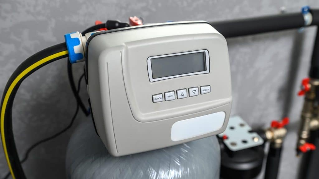 Close-up of a water softener control valve head with bypass valve and PEX supply lines
